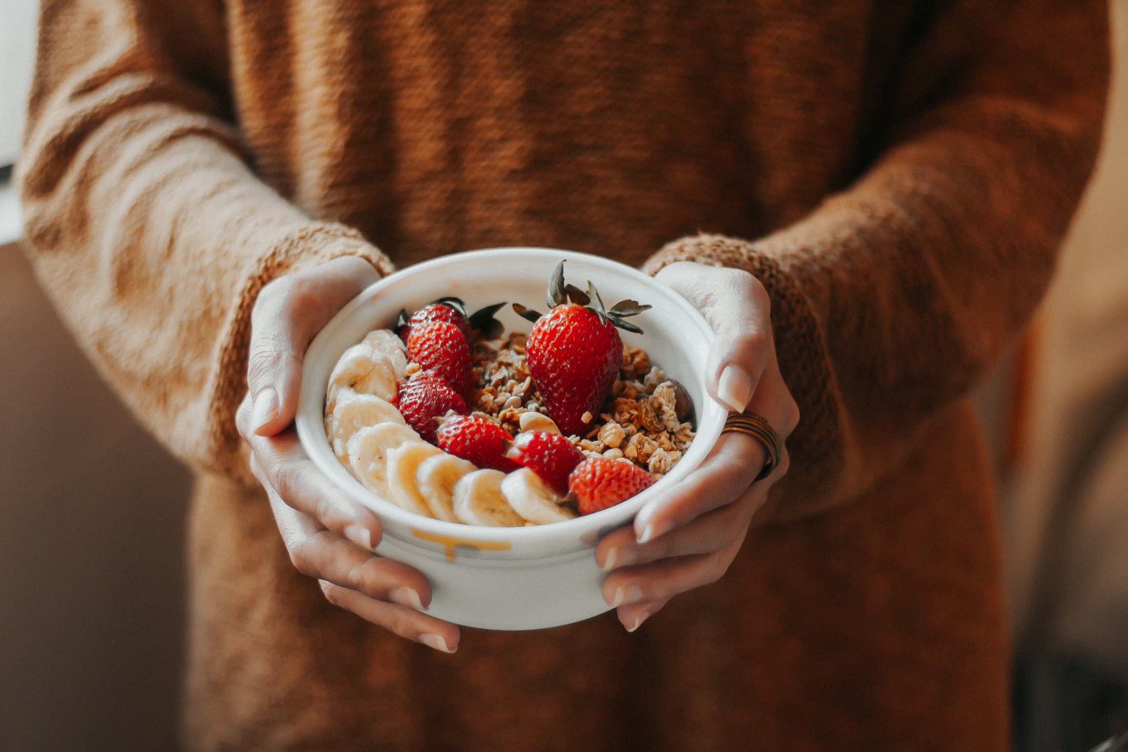 Woman Holding Bowl of Granola with Banana and Strawberries 